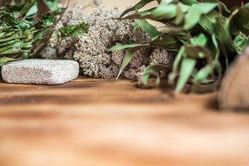 Various sauna accessories in a wooden Finnish sauna or Russian bathhouse with traditional sauna accessories: birch broom, felt hat,pumice, birch wood medicinal herbs. Relax concept. Copy space