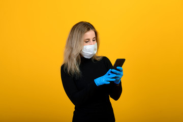 Portrait of a girl in a medical mask, which puts on a rubber glove. Yellow and grey background. Copy space.