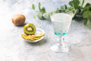 Cold cocktail kiwi drink in a glass with fresh fruits on gray background
