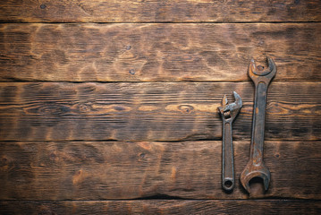 Old wrenches on brown wooden workbench background with copy space.