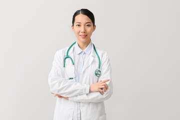 Female Asian doctor on light background