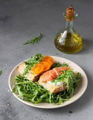 Healthy open sandwiches with artisan bread with cream cheese, salmon, tomatoes and arugula on ceramic plate. Balanced diet concept. 