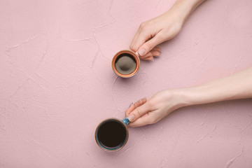 Female hands with cups of coffee on color background