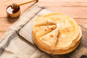 Tasty blini with honey on table