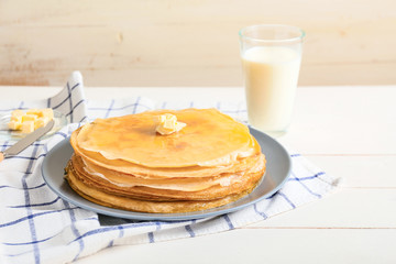 Tasty blini with butter and milk on table