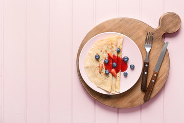 Tasty blini with berries on table