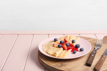 Tasty blini with berries on table