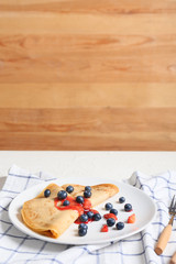 Tasty blini with berries on table