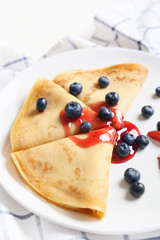 Plate with tasty blini and berries on table, closeup