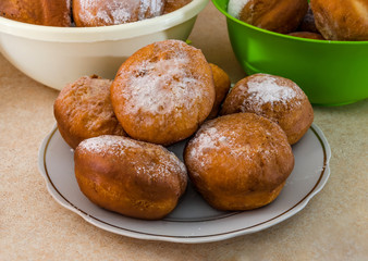 Ukrainian round donuts in a plate on the table. Lots of delicious donuts with powdered sugar.