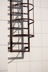fire metal staircase on a building tiled wall. vertical view