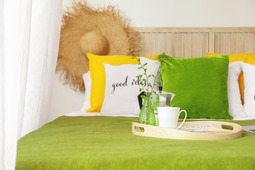 Tray with coffee and vase with spring tree branches on bed