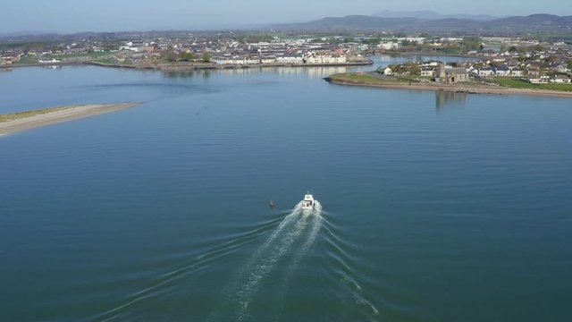 Aerial flying above boat on calm ocean water in Waterford, Ireland in summer