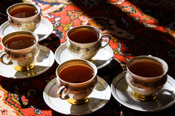 vintage soviet porcelain cups of tea with saucers on turkish carpet, traditional tea ceremony,...