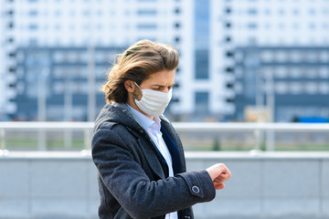 Young man in a medical mask outside, no money, crisis, poverty, hardship. Quarantine, coronavirus, isolation.