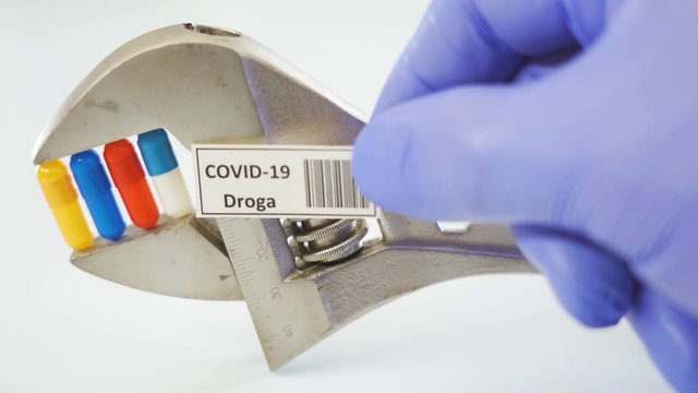 The lab doctor in blue gloves holding the sign for coronavirus or Covid-19 droga written in Italian