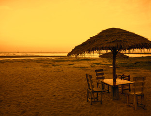 Sitting to eat under the coconut leaf visor at the beach in the evening