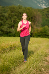 Beautiful young woman workout outdoor runs across meadow in early summer