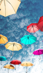 Colorful umbrellas fly under the sky. Concept of good mood, nice weather. Vertical cropping.