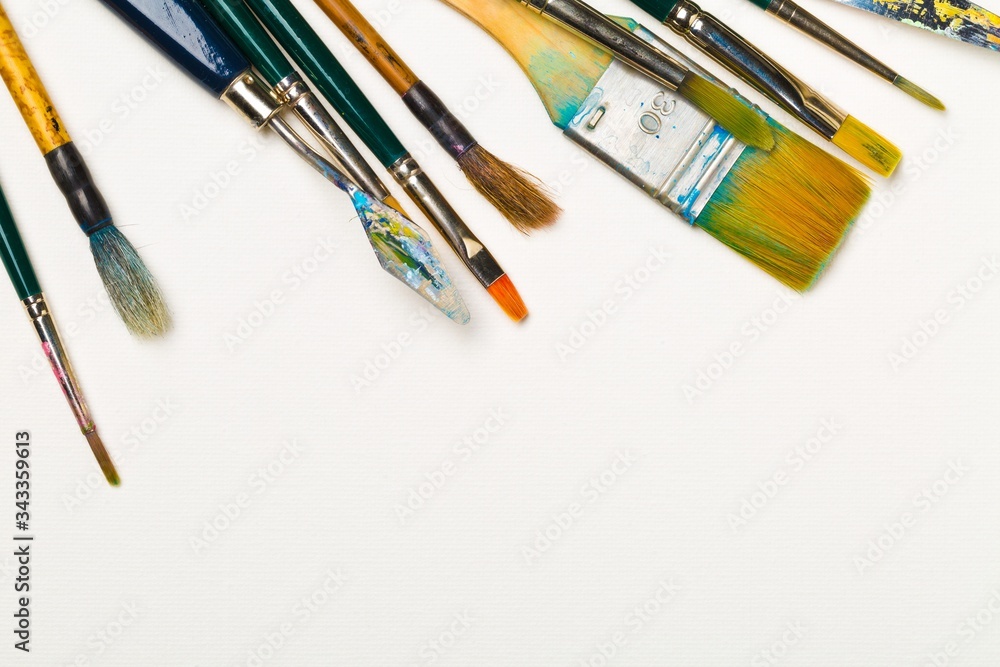 Poster artistic art supply utensils with brushes on white background with copy space flat lay top view from