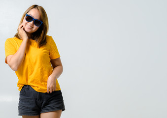 Beautiful young woman with yellow t-shirt and sunglasses feeling funny happy on white background,Summer concept banner background.