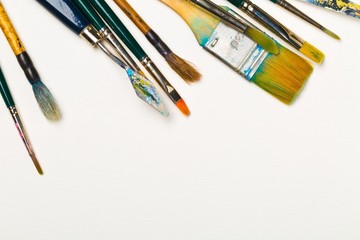 Artistic art supply utensils with brushes on white background with copy space flat lay top view...
