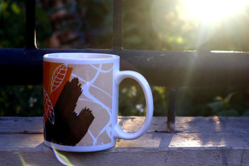 Coffee mug on a fence with beautiful sunset in the background