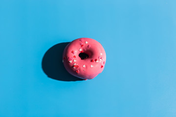 Colourful round donuts at bright blue background. Sweet donuts. Trendy sunlight Summer pattern Minimal summer concept. Pink donut.