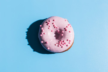 Trendy sunlight. Doughnut on bright light blue turquoise background. Minimal summer concept. Pop art style. Pink donut.