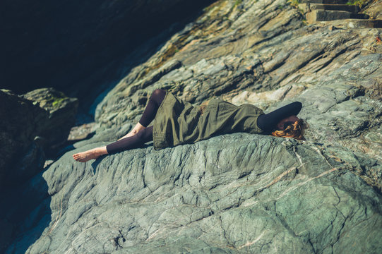 Pregnant woman lying on a rock in the sun