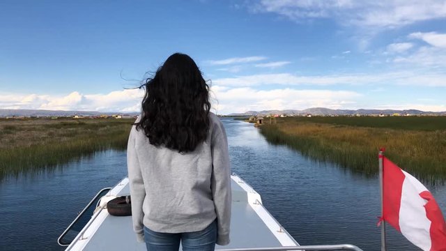 Tilt down shot of a Peruvian Spanish young girl visiting Uros Islands. Pretty girl on a boat on the way to the Uros Islands, in Puno. Chica joven en un bote direcci&oacute;n a las Islas flotantes de Uros..