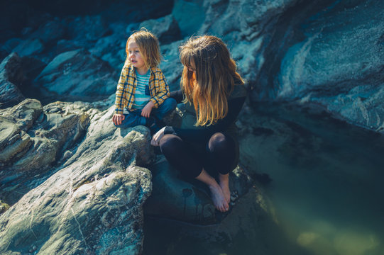 Mother and preschooler sitting by rock pool