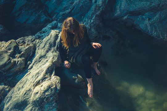 Young woman dipping her toes in rock pool