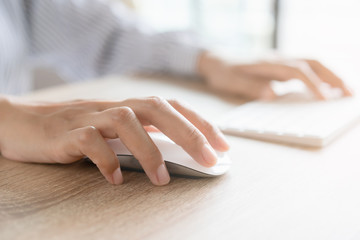 Close up of business woman hand typing on computer keyboard with the mouse while sitting working on...