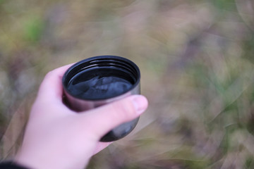 Man holding a thermal travel cup isolated with a blurred background