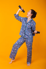 Smiling young girl in pajamas home wear posing while resting at home isolated on yellow background studio portrait. Relax good mood lifestyle concept.