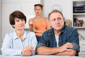 Obraz premium Upset female and her husband are sitting at the table and their daughter is sympathying with them