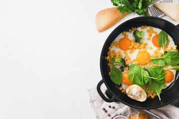 Healthy breakfast table with fry pan eggs with spinach on white background with copy space top view