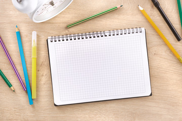 School spiral notebook with markers on wooden background top view