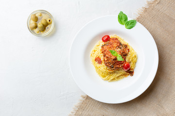 Italian pasta in a white plate with tomato sauce, basil, olive, concrete. sackcloth. Top view