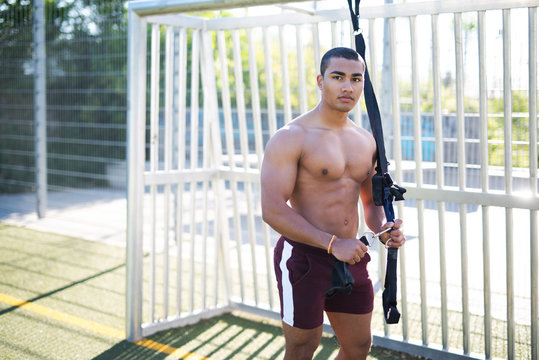 Cooler und muskul&ouml;ser junger Mann trainiert im Freien mit einem Schlingentrainer 