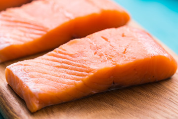Delicious salmon steak on wooden cutting board, close-up.