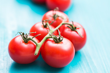 Close-up of fresh ripe cherry tomatoes on turquoise wooden background.