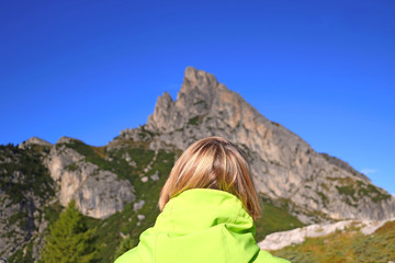 A girl looks at the Dolomites in Italy. Back view. Selective focus.