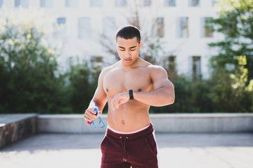 Mann mit freiem Oberk&ouml;rper schaut beim Training auf seine Fitnessuhr
