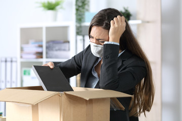 Fired executive with mask packing belongings at office