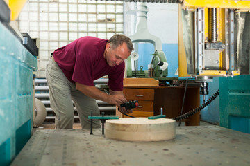 Elderly worker fixes wooden workpiece in 3d machine