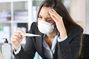 Worried executive with mask looking at thermometer