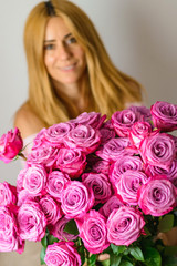 Woman receive a big bouquet of pink roses .