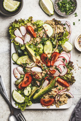 Quinoa salad with tomato, cucumber, radish and avocado on gray plate, top view. Healthy vegan food concept.